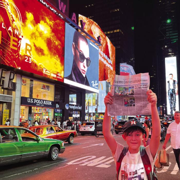 Just like one of the New York newsboys of old, Maddox Wick is shown here hoisting up a copy of The Fayette County Record at Times Square last week. But this copy was not for sale, it traveled with Maddox and his dad, Record editor Jeff Wick, as they took an Amtrak train trip across the country. They visited St. Louis, Chicago, Niagara Falls, New York City and Washington D.C. by train before flying home.