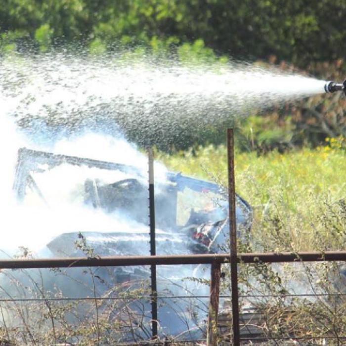 A La Grange volunteer firefighter sprays off a travel trailer that burned as part of the Plum Church Road Fire. Photo by Jeff Wick