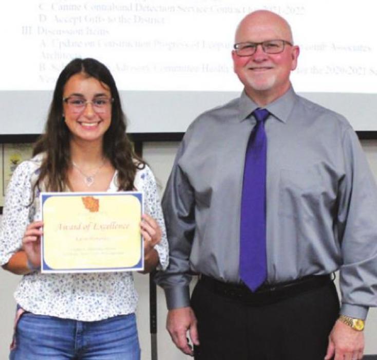Board president Gary Drab presented Kalyn Hernandez, left, with an Award of Excellence for her artwork being named Grand Champion at the Austin Rodeo.