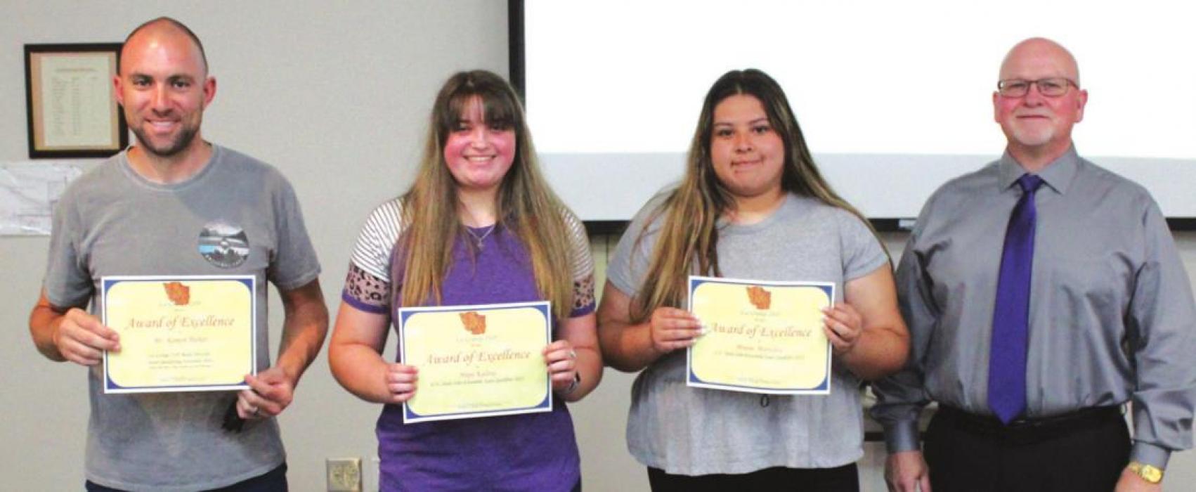 Board president Gary Drab presented Hope Kalina and Maise Martinez, second and third from left, with Awards of Excellence for advancing to state in band Solo and Ensemble performance. Their band director, Ramon Parker, left, was also presented an Award of Excellence.