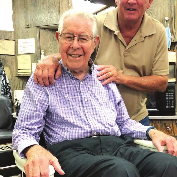When Ken moved to his new barbershop, he relocated his two 106-year-old antique barber chairs and the mirrors behind them. The chairs, which were manufactured by Emil Paidar Co. of Chicago in the early 1900s, have stood the test of time as both Ken (standing) and Charlie (seated) attested. (Elaine Thomas shot this photo several weeks before the state and citywide masking order.)