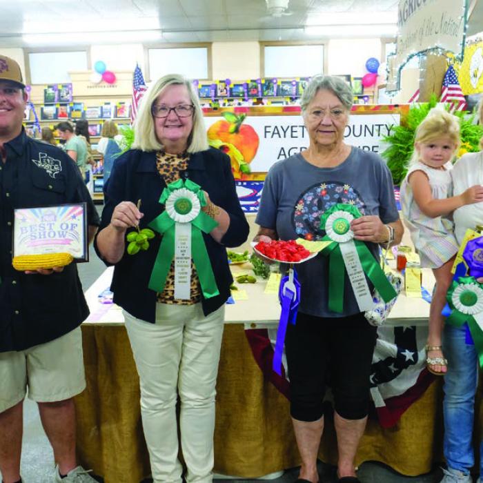 BEST OF THE AGRICULTURE DEPARTMENT From left, best of show in the ag department and grand champion farm products went to Matt Joost and Joost Ag Partners for 10 ears of corn; grand champion pecans went to Becky Garlick for a plate of Kiowa pecans; grand champion garden products went to Dr. James Tiemann (represented by his wife Nita Tiemann) for a plate of habanero peppers; grand champion honey went to to Whitney Bass, who is being held by reserve champion honey winner Ann Lyons.