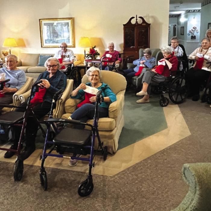 Sacred Heart Catholic School sixth graders, left, sang Christmas songs and delivered stockings stuffed with goodies to the residents at Jefferson Place, right. This is one of the many traditions and service projects their students do each year.