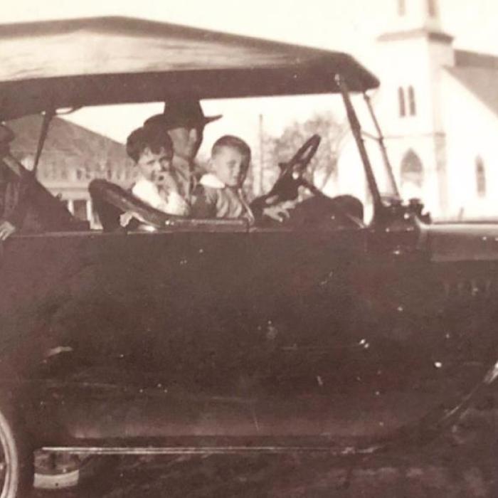 Edward Stanzel Sr. was taking his sons for a ride in Schulenburg circa 1918. In the back seat is Victor, while Joe (left) and Reinhart (right) sit up front. In the background is St. Rose of Lima Catholic Church.