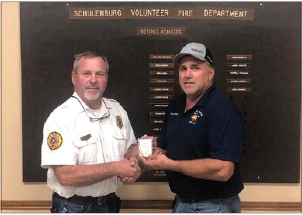 Outgoing Schulenburg Fire Chief Jeff Proske (left) presents the chief’s badge to newly elected Fire Chief Darren Guentert at the department’s meeting last Thursday, Sept. 14.