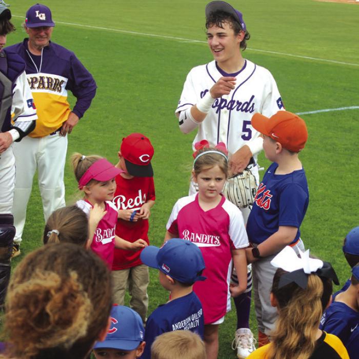 Varsity players joke around with the Little Leaguers pregame.