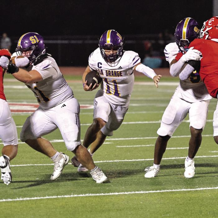La Grange quarterback Eli Gillum runs through a hole created by blockers, Sterling Walla (51, left) and Dillan Johnson (9, right) in Friday’s game. Photo by Darrell D. Gest