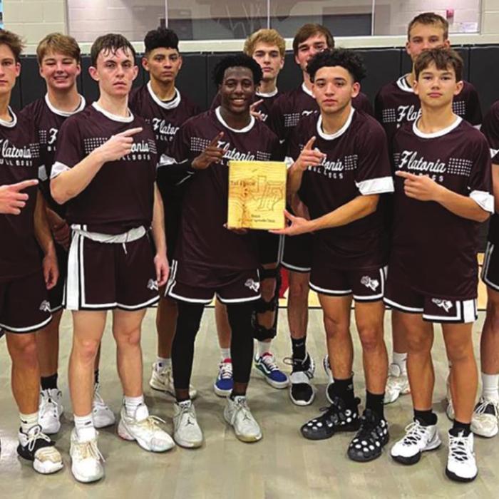 The members of the Flatonia Bulldogs varsity basketball team hold up their championship trophy after winning the Fayetteville Tournament Saturday.