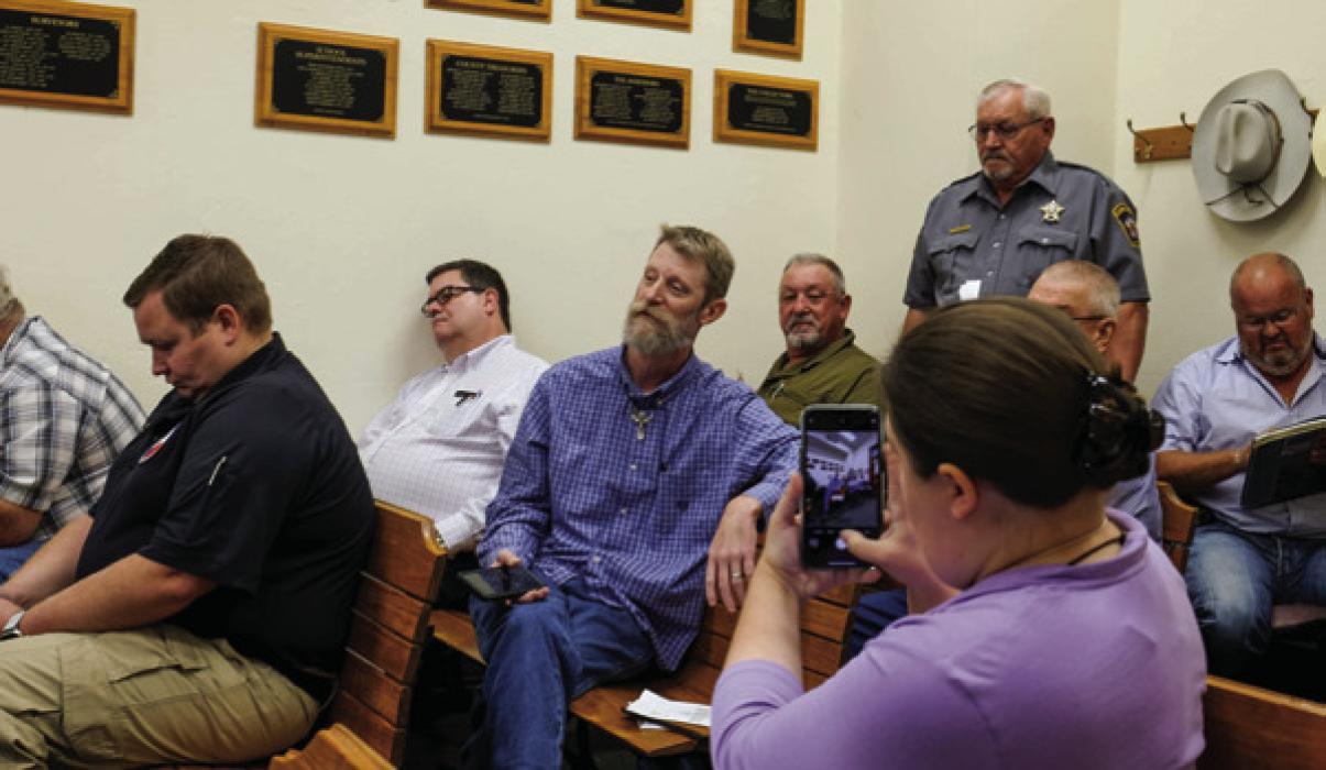 William Bernsen, center, speaking at the Fayette County Commissioners Court meeting last Thursday, while Pct. 1 Constable Billy Roensch (standing) prepares to escort him out of the room. Photo by Andy Behlen