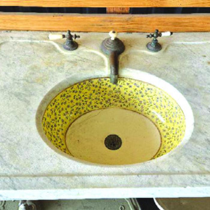 Marble sink with decorated bowl and mixed hardware.