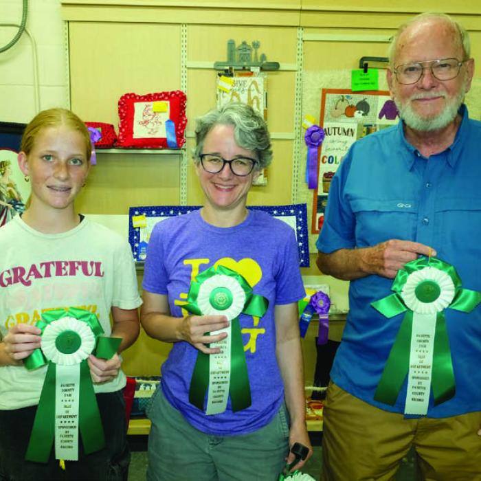 BEST OF THE MACHINE SEWING FABRIC AND FIBERS DEPARTMENT Pictured (from left) are Cayden Nelius - 13 to 17 year olds - fabric book, Monica Smith - 18 and above - red toiletry bag, and Harvey Hansen - 70 and above - “Autumn is my Favorite Color” wall hanging.