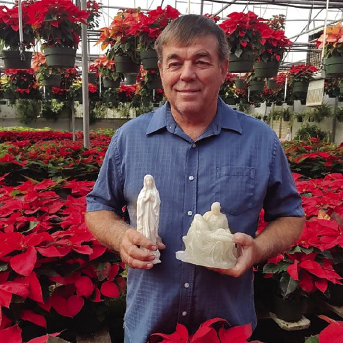 Doug Janda’s day job may be running his business, Hostyn Hill Greenhouses, but he’s been passionate about repurposing remnants of the old Hostyn church like the statues he’s holding in this picture. Photo by Jessica Montez
