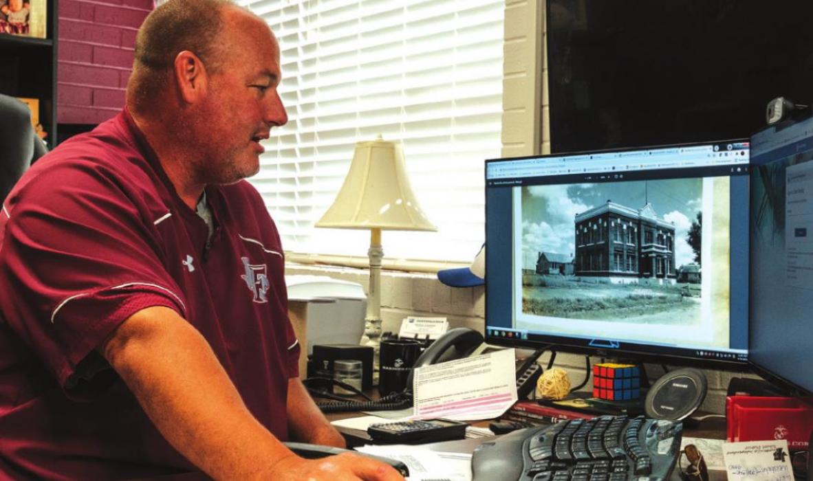Fayetteville superintendent Dr. Jeff Harvey at his desk with an scanned image of the schoolhouse from 1944 on his computer screen. Photos by Andy Behlen