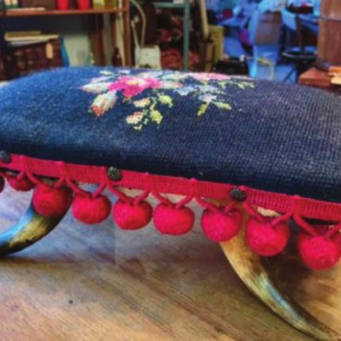 Examples of Antiques Found around Fayetteville Antique footstool with horn legs and pompom fringe.