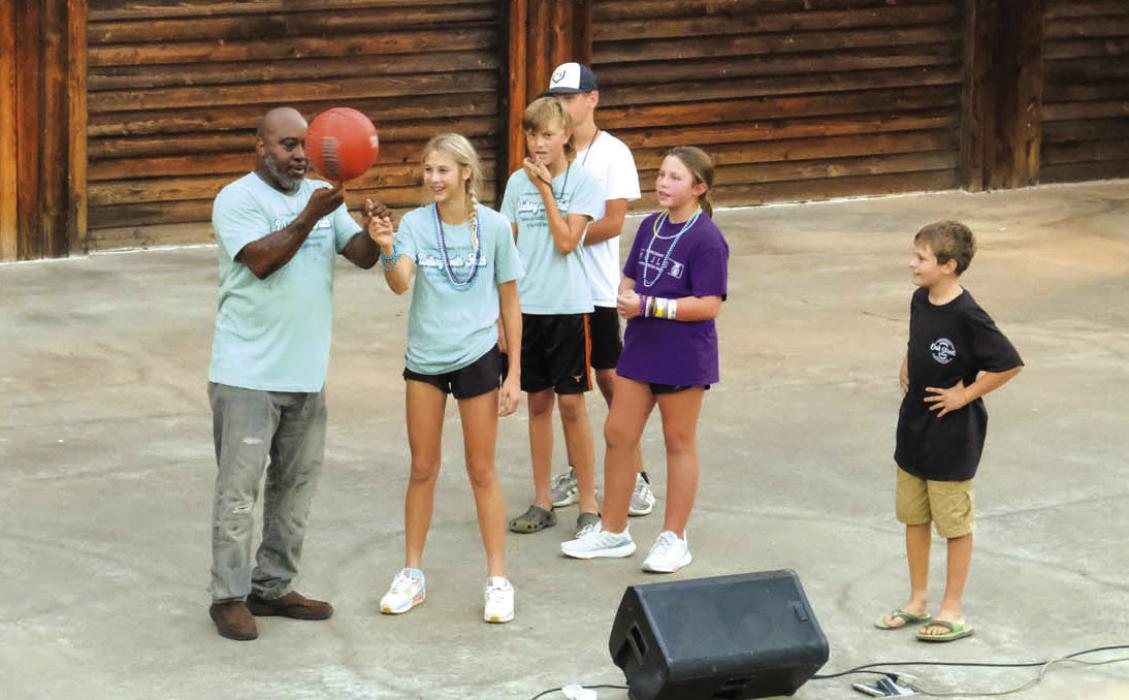 Motivational speaker and former professional basketball player Melvin Adams shows a basketball trick to Kinley Tillery.