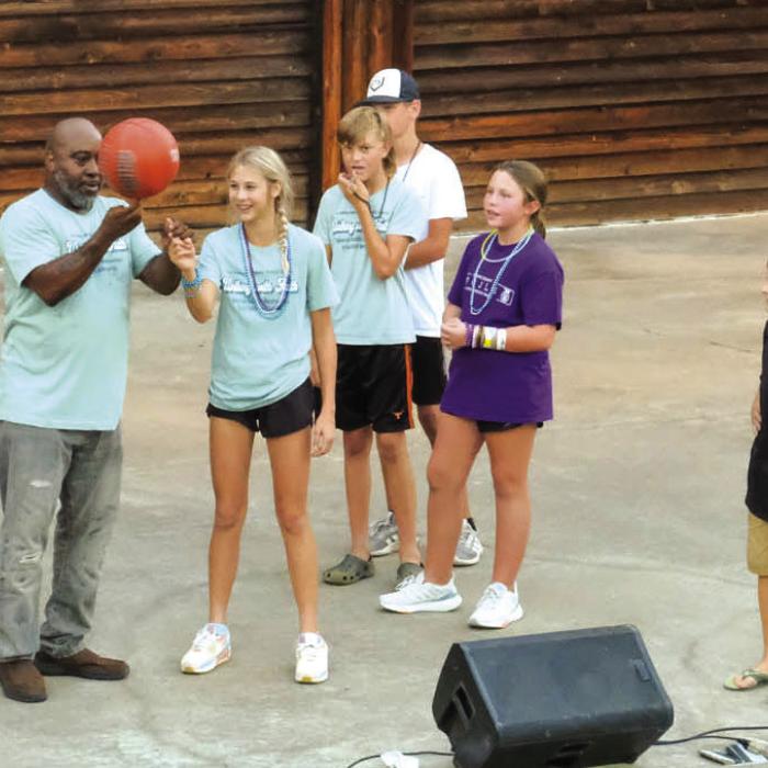 Motivational speaker and former professional basketball player Melvin Adams shows a basketball trick to Kinley Tillery.