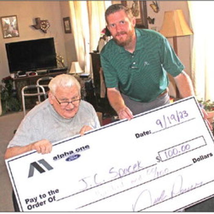 J.C. Spacek of La Grange, above left, seated, is shown here collecting his $100 prize from Nick Power of Alpha One Ford after winning last week’s newspaper reader football pick it contest. Spacek turned in one of eight perfect 10-for-10 ballots last week. His score prediction tiebreaker of the Cowboys game vaulted him to the win. The ballot is included in every Tuesday edition of The Fayette County Record. The contest is sponsored by Alpha One.