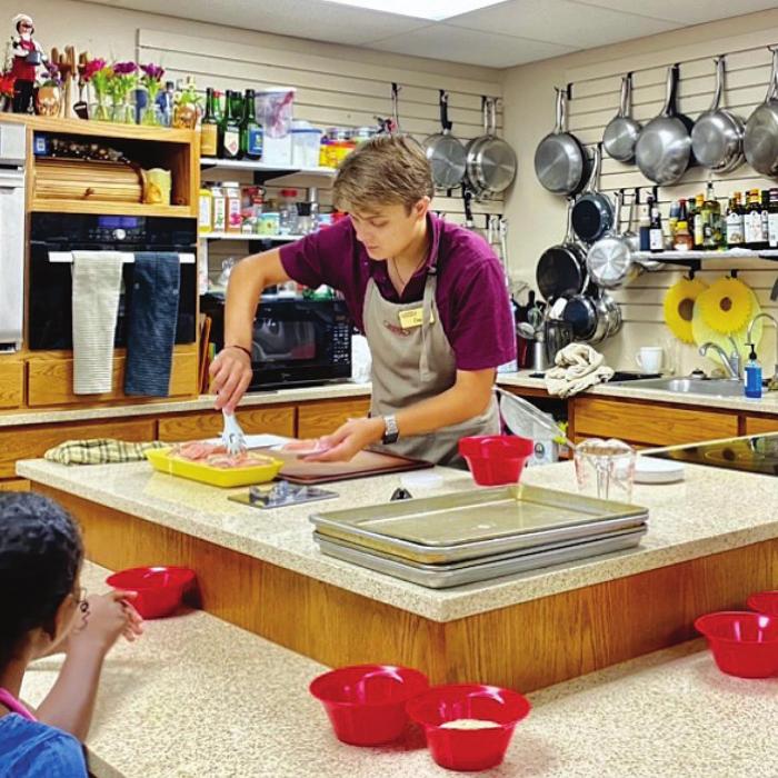 Instructor Coy Heinrich teaches youngsters how to cook at Le Petite Gourmet Shoppe’s Kids ‘N The Kitchen classes, which take place throughout the summer.