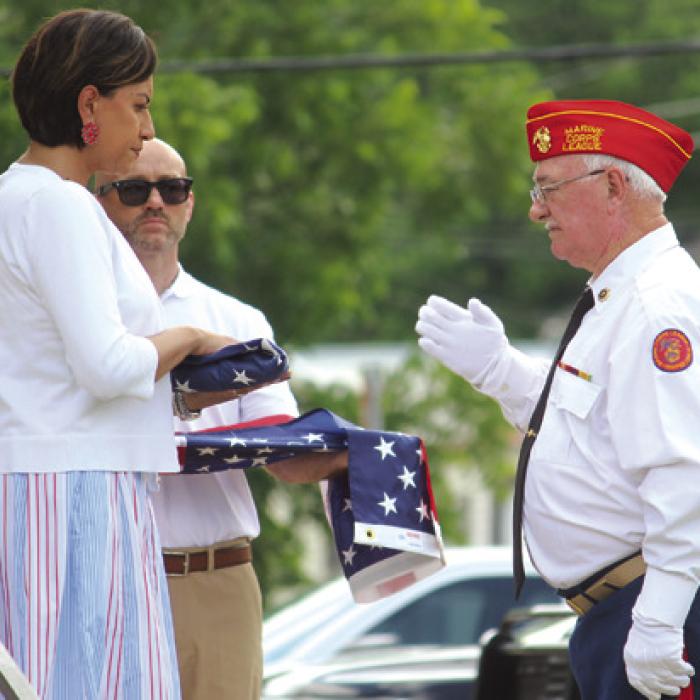 A member of the Marine Corps League #1028 presents a folded flag to Amber Belvill-Carroll after the League retired the colors Monday.