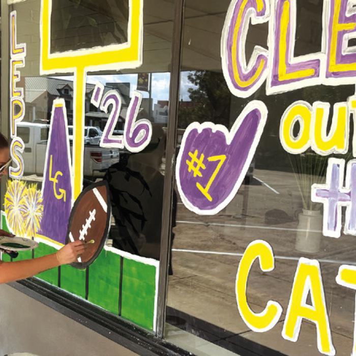 Carrie Harbers was out painting the Clear Title Company window on the courthouse square Tuesday afternoon for homecoming, which is Oct. 9. Photo by Jeff Wick