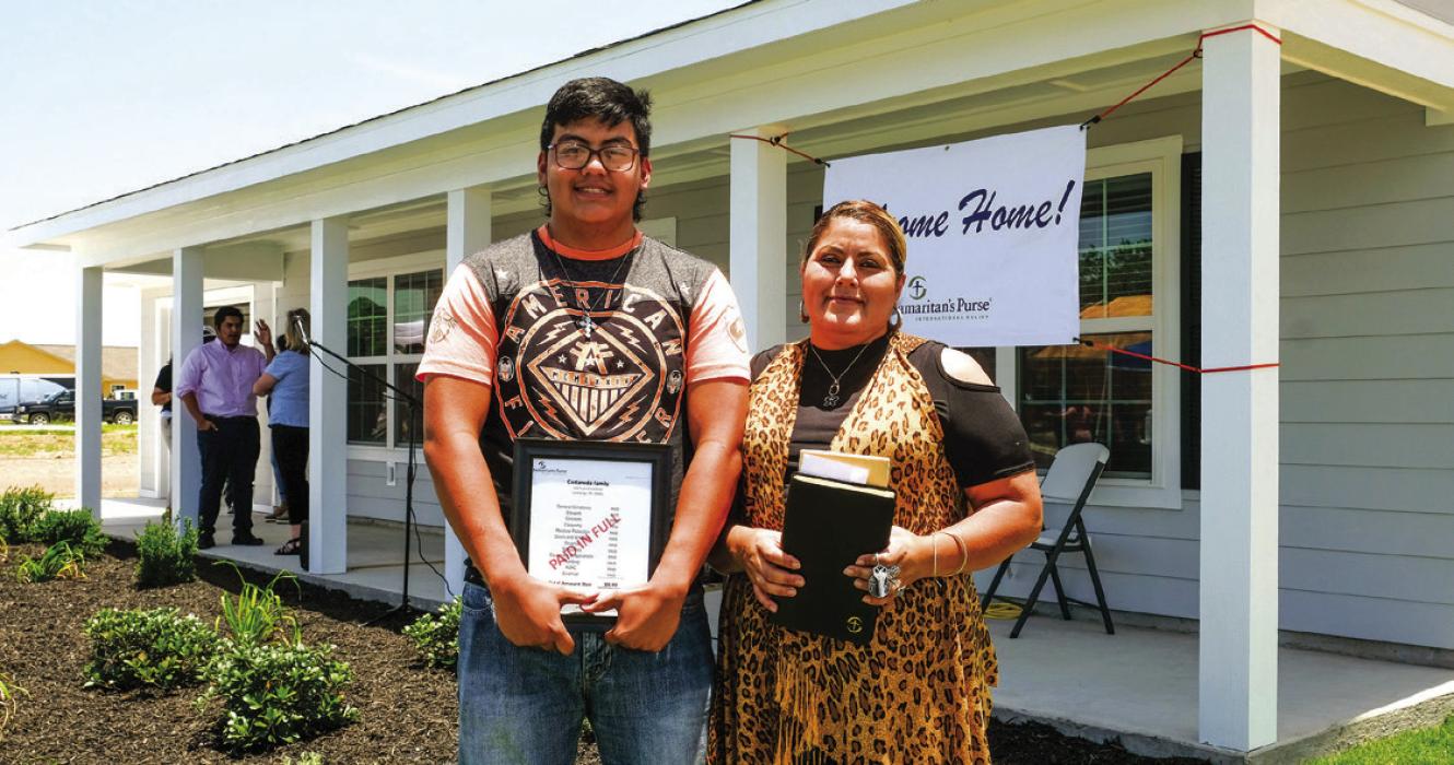 Jose and Francisca Castaneda hold a bible and a bill stamped “paid in full” in front of their new home in Hope Hill in this June 2020 photo. They had lived in La Grange for 10 years before they lost their home in Hurricane Harvey. They were one of the first families to get a home in Hope Hill.