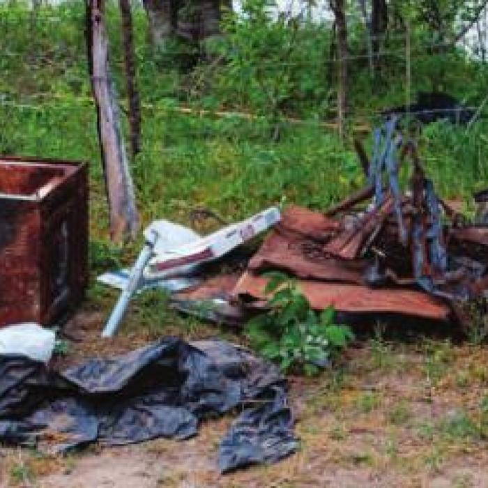 The remnants of a trash fire included a lid to a barbecue pit with dozens of bullet holes, indicating someone has been shooting at the end of the road.