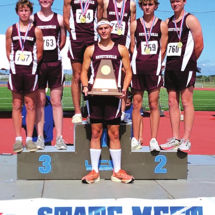 The Fayetteville boys cross country team holds up their regional championship trophy after winning the title Monday in Corpus Christi.