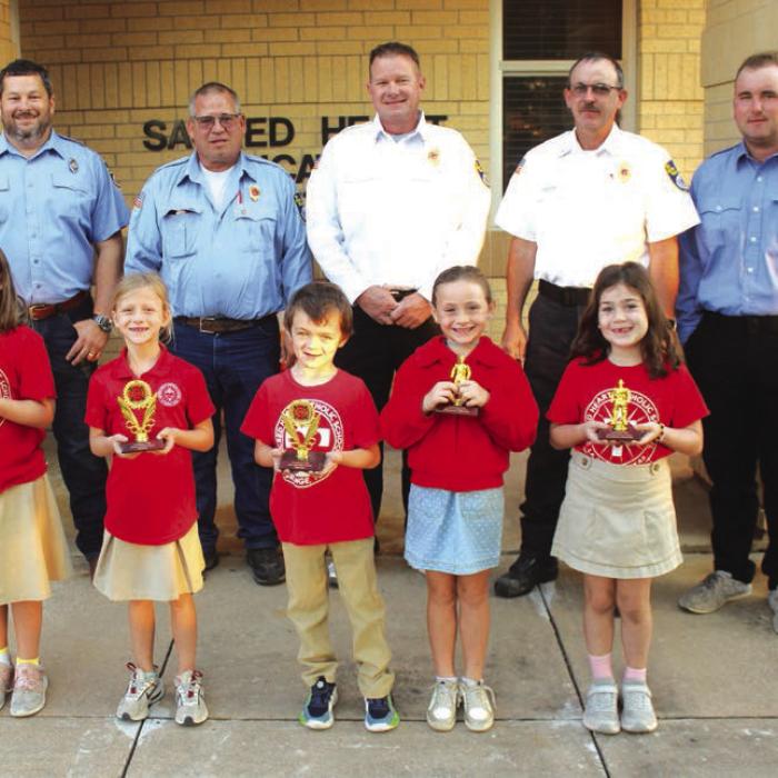 1st and 2nd Grades – Left to right, Winners: Claire Stewart, Quinn Hatfield, Rhyatt Sarvis; Honorable mention: Corbyn Blackwell, Cheyenne Morales, Reeanna Ramirez (not pictured). La Grange firefighters Chris Kaspar, Kenneth Chovanec, Todd Johnson, Glen Knigge, and Blythe Vitek. Photo by Jeff Wick