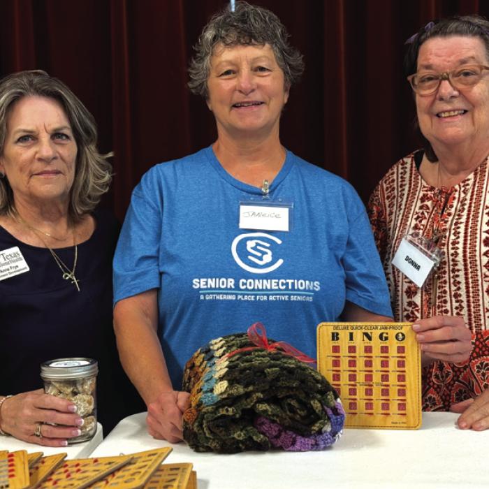Anne Frye with First Texas Home Health holds a jar of cookies in thanks for calling our bingo game in Weimar. In the center is Janice Collins, a valued volunteer, holding her prize from the blackout game. Donna King made the crocheted blanket on the right.