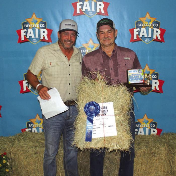 Mark Vecera won first place in Class 4 at The Fayette County Fair Hay Show Thursday. Vecera is shown right holding his hay which sold for $1,050. Left is buyer Matt Arthur of Bumper Crop Texas.