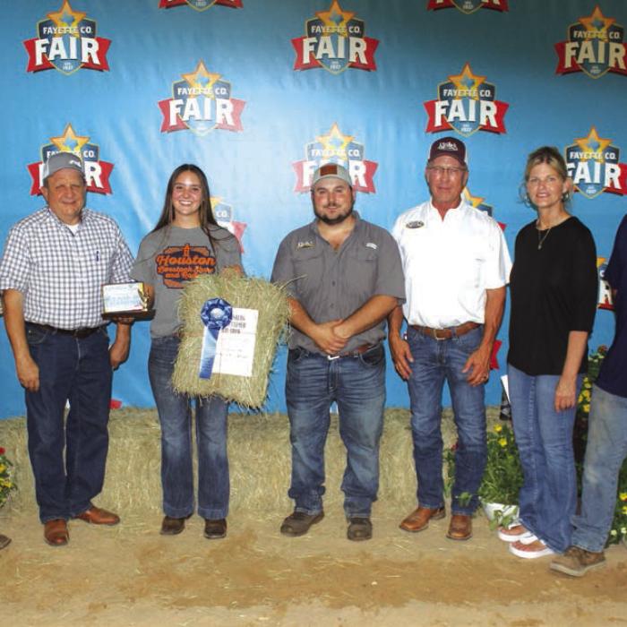 Stryk Jersey Farm won first place in Class 3 at The Fayette County Fair Hay Show Thursday. Mikayla Stang is shown here holding the hay, which sold for $1,000. Left to right are the buyers – Kent Ohnheiser of M-G, Rodney Kalich of Fayette Savings, Mikayla Stang, Ryan Kleiber and David Kleiber of Kleiber Tractor, Susan Wick of Tex Propane and Daniel Wick of Wick Water Well Service.