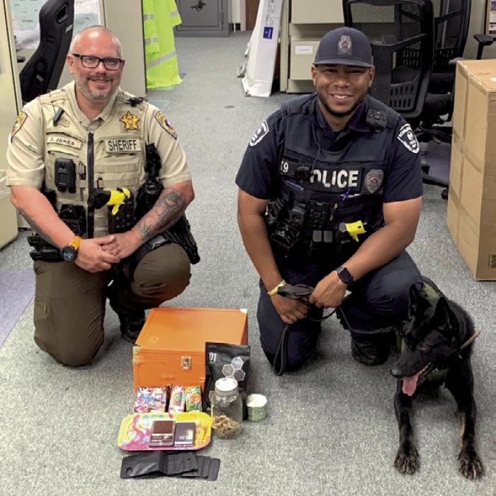 Deputy Josh Jones, Officer Byron Powe, and K9 Semper pictured with the marijuana, vape pens containing THC oil, mushrooms, scales, packaging material and drug paraphernalia recovered during search of the vehicle.
