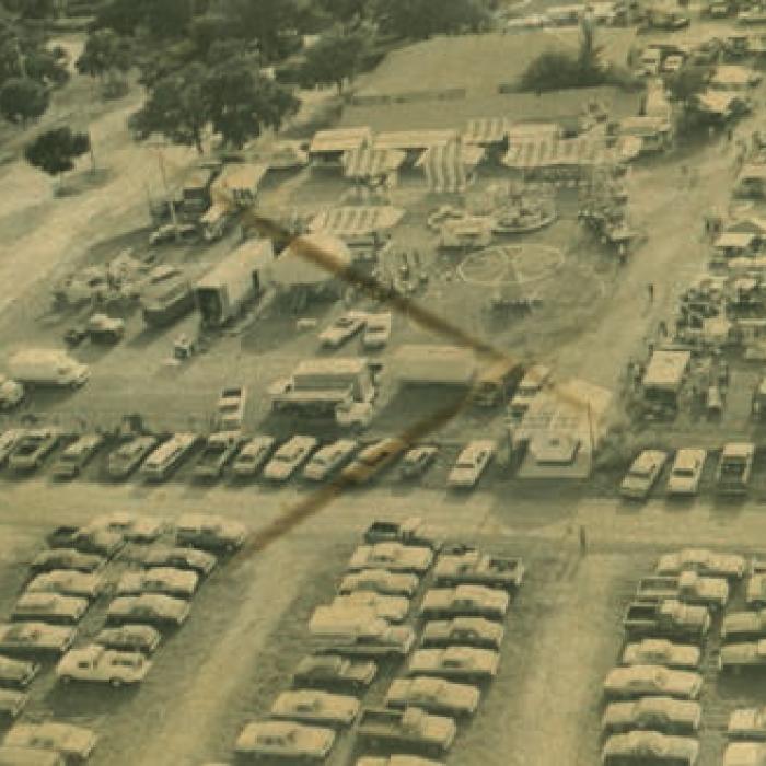 The Fayette County Fairgrounds 1975 aerial shot during the Fayette County Fair featuring the carnival rides, dance hall and parking. 