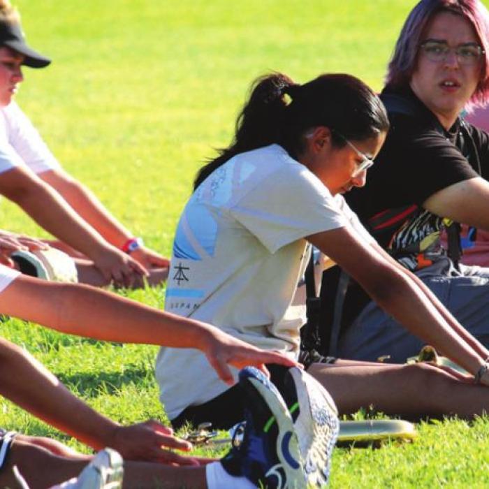 Students stretch outside on the marching field before beginning marching drills.