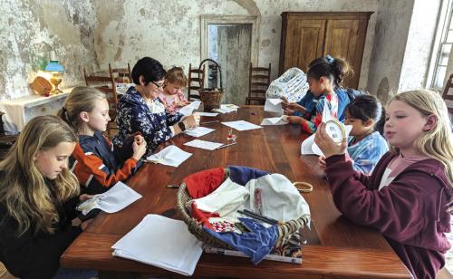 Guests gather around the table in the Kreische House to hone their sewing skills.