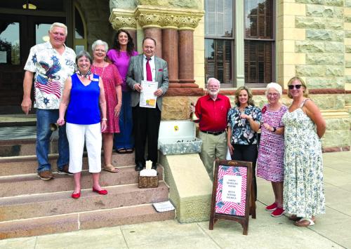 Pictured front from left on the courthouse steps is: Kathy Schatte, Constitution Week Chairman; second row: Jerry Schatte; Sherry Hebert, Chaplain; Cassie Austin; Judge Dan Mueller; beside the steps from left: Larry Jackson; Jamie Fabre; Carolyn Caflisch, Registrar; and Gina Minzenmeyer, Regent, Smith-McMillan Chapter, NSDAR.