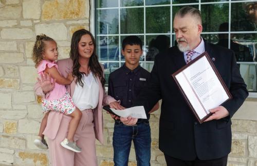ce to the new Round Top Postmaster, Hannah Hollmann, on Friday, April 24. Also pictured are Hollmann’s children Ember and Evander. Pictured below are Hollmann and Biskner with several of Hollmann’s family members, colleagues and officials from the Town of Round Top. James Biskner (right), manager of post office operations for this region, delivers the oath of offi