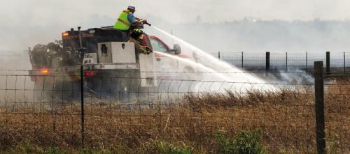 An Ellinger fire crew sprays down the corner of a burning pasture. Photo by Andy Behlen