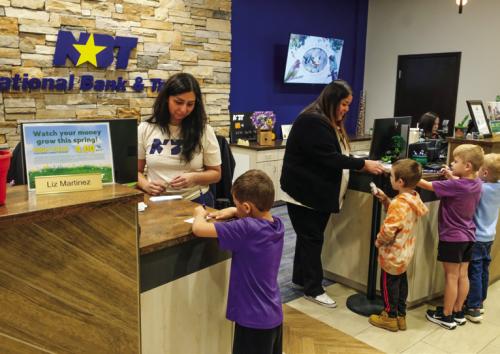 Student practiced signing their name on deposit slips with the tellers at the front of the bank. Photos by Andy Behlen