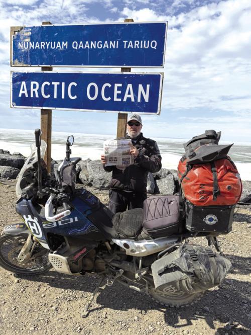 Chris Westfall stands at the sign marking Tuktoyaktuk, Northwest Territories, the northernmost community in Canada accessible by road, after completing an 11,724-mile motorcycle journey. Westfall timed his arrival for the June 21 summer solstice to experience the Arctic’s famous “midnight sun.”