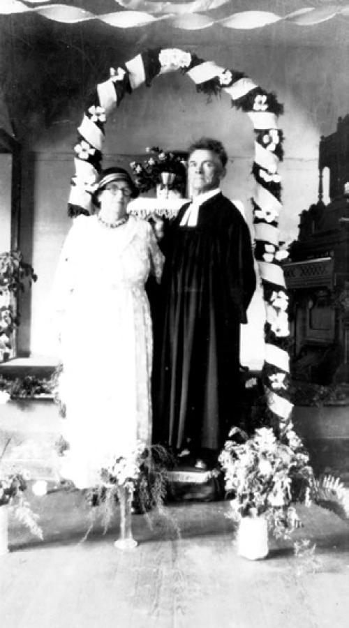 Minna and Rev. Carl Baer standing under a decorated arch in 1935, courtesy of the Fayette Heritage Museum and Archives.