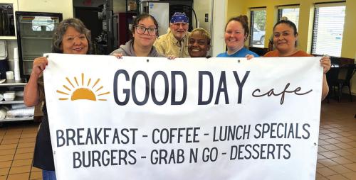 In the midst of a trial run of lunch service Wednesday, the employees of Good Day Cafe in La Grange posed with a sign that was placed outside the business Friday. The new cafe is now open for lunch in the old Hank’s Express spot at 154 S. Jefferson Street. They plan to add breakfast service soon. Photo by Jeff Wick