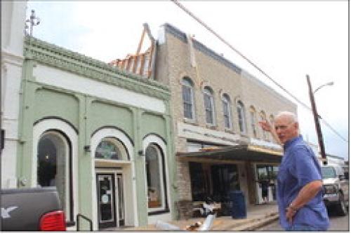 Flatonia’s Mike Steinhauser points to how the roof of his law office downtown was peeled off by powerful winds Thursday night. Photo by Jeff Wick