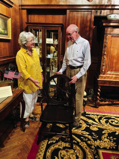 Lamar Lentz, Library and Museum Collections Curator, and Pat Johnson, Associate Curator, install the “Old Flax Spinning Wheel Chair,” an example of Colonial Revival folk art produced around the time of the 1876 Philadelphia Centennial, in the Round Top Festival Institute collection.