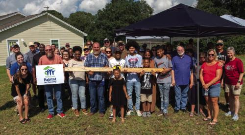 Johnny Wright (center), surrounded by family, friends, Habitat for Humanity volunteers and local supporters, stands on his future homesite in the Hope Hill neighborhood of La Grange. They’re holding a signed 2x4 with words of support that will be used in the construction of his future home. Photos by Andy Behlen