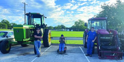From left to right, La Grange High School students Luke Chovanec, Alan Hepner and Mason Oppermann with the machines they drove to school Friday. Chovanec and Oppermann drove their tractors, and yes, that is Hepner sitting atop a push lawn mower. Photo by Deacon Wick