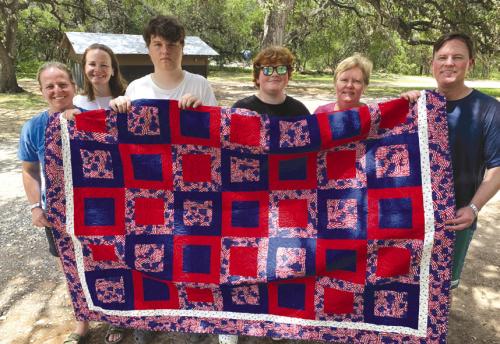John Tajchman was presented a Quilt of Valor by his mother Marian. He served as a Sargent in the U.S. Army Intelligence from 2000-2004. John is on the right side of the quilt surrounded by his mother, sisters, and nephews. The quilt was made by the members of the Colorado Valley quilt Guild here in La Grange.