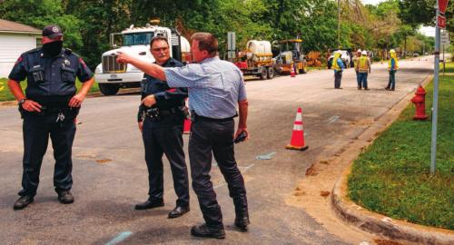 Patrolman Curtis Zwahr and Sgt. Travis Anderson of the La Grange Police Department and La Grange Fire Chief Frank Menefee make plans to evacuate the neighborhood after a gas leak at the corner of Milam and Jackson streets Monday afternoon. A contract crew working for Centerpoint Energy (pictured in the background) accidentally struck a four-inch gas line while digging with an excavator. Photo by Andy Behlen