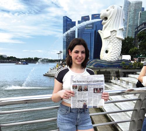Jane Griffith, 16, travelled to Singapore, Malaysia, Thailand and Japan this summer, spending six weeks in Singapore in a language immersion program studying Mandarin Chinese. She brought the Fayette County Record with her. She chose the issue reporting encounters with the new pope, as his selection brought her a lot of joy. Here she is posed at the famous Merlion statue in Singapore, a mythical creature that is a symbol of the city.