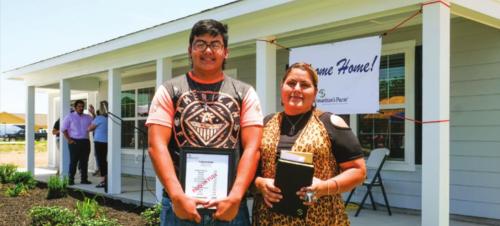 Jose and Francisca Castaneda hold a bible and a bill stamped “paid in full” in front of their new home in Hope Hill. Photo by Andy Behlen